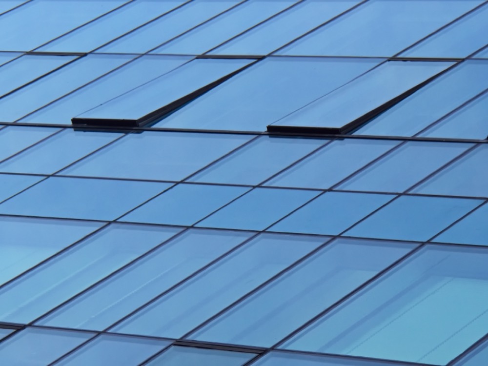 A blue-glass corporate building against a clear sky, representing the emerging Creditcorp brand identity