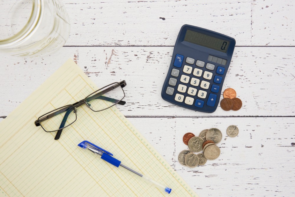 A calculator, invoices and a notebook on a desk — a director working out short-term cash needs against a term commitment