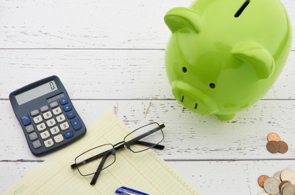 A piggy bank beside coins, representing setting tax money aside ahead of the bill