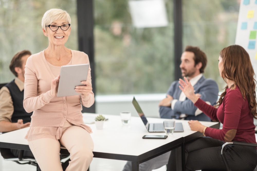 A marketing team gathered around a laptop in a bright office, working through a campaign